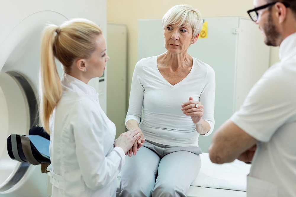 Worried mature woman undergoing for MRI scan examination and communicating with doctors before the procedure in the hospital.
